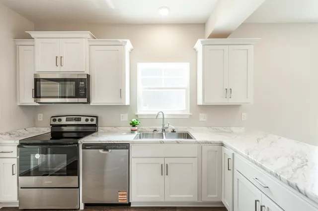 a kitchen with stainless steel appliances granite countertop white cabinets sink and stove