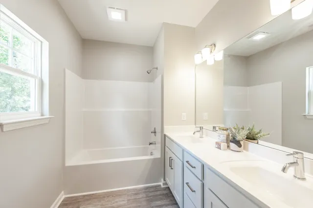a en suite bathroom with double vanity a mirror and a bathtub