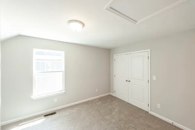 an empty room with closet and windows