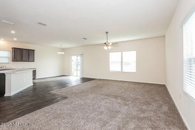 an empty room with windows and chandelier fan