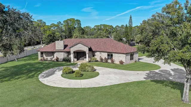an aerial view of a residential houses with outdoor space and trees
