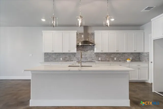 a kitchen with kitchen island sink stove and cabinets