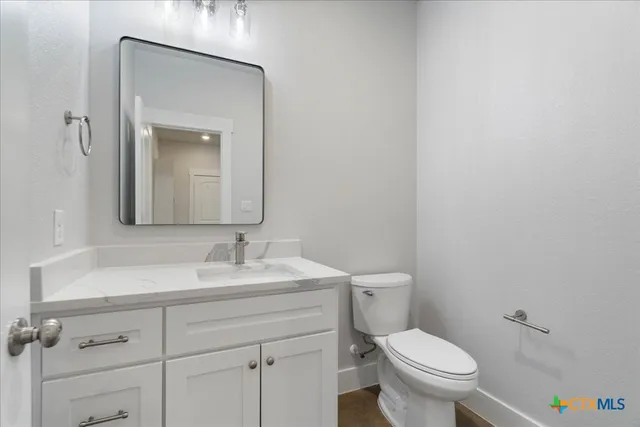 a bathroom with a toilet sink vanity and mirror