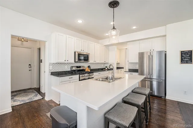 a kitchen with a refrigerator a stove a sink and white cabinets