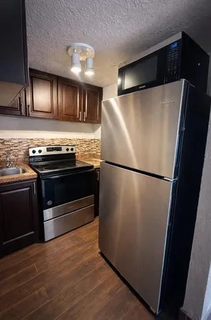 a kitchen with granite countertop a refrigerator and a stove top oven