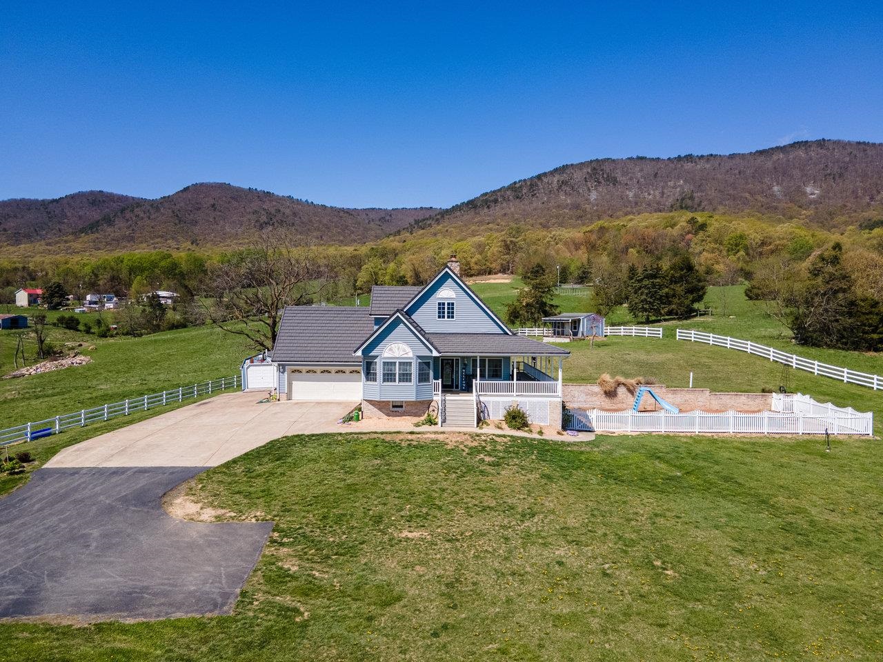 a front view of a house with a yard and a large tree