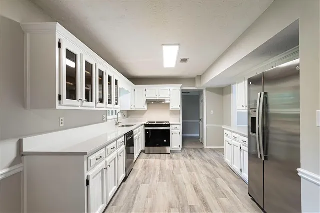 a kitchen with stainless steel appliances a stove top oven a sink and a refrigerator