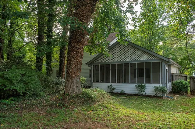 a view of a house with a yard plants and large trees