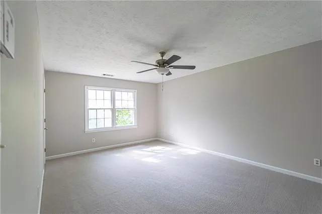 an empty room with a window and a ceiling fan