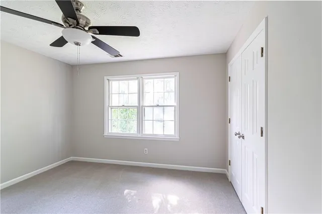 an empty room with windows and fan