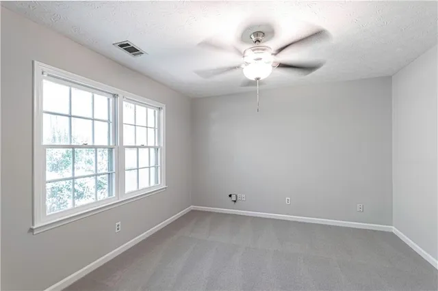 an empty room with windows and fan