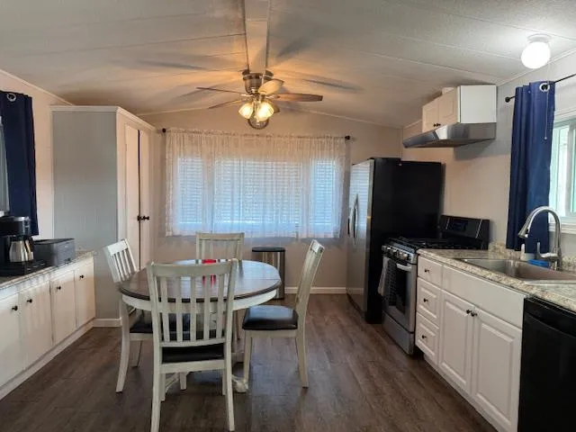 a kitchen with granite countertop a sink cabinets stainless steel appliances and a window