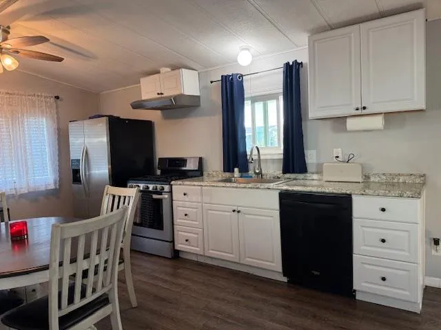 a kitchen with stainless steel appliances granite countertop a dining table chairs refrigerator a sink and dishwasher