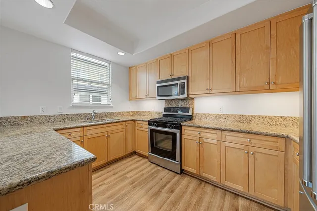 a kitchen with granite countertop cabinets stainless steel appliances a sink and a window