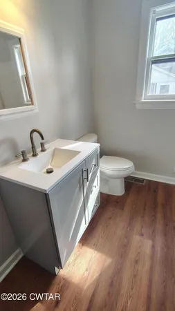 an empty room with wooden floor and a bathroom