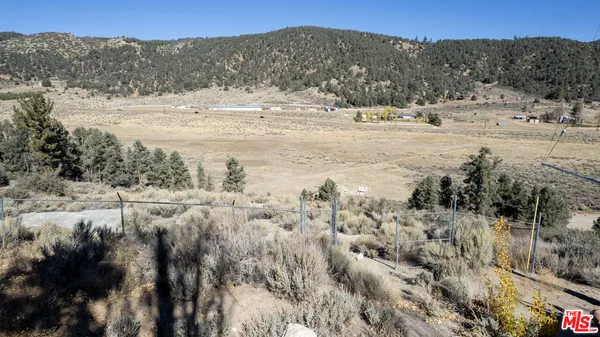a view of a dry field with mountains in the background