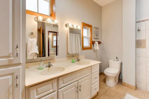 a bathroom with a double vanity sink toilet and a mirror