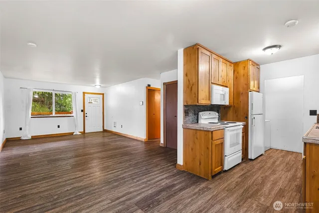 a kitchen with stainless steel appliances granite countertop a refrigerator a stove a sink and dishwasher with wooden floor