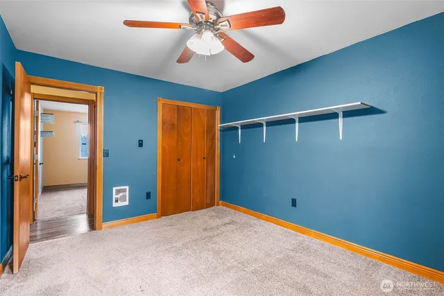 an empty room with closet and a chandelier fan