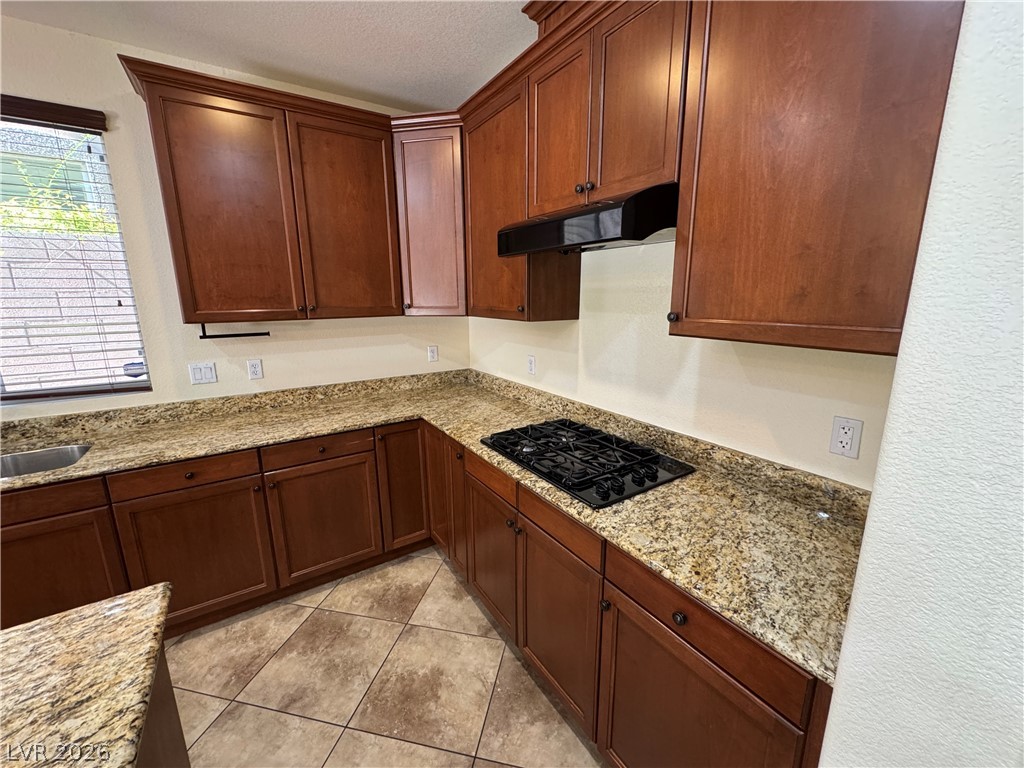 1333 Jamesbury Road Las Vegas, NV 89135 - Photo 18 of 43 A corner kitchen features rich wood cabinetry, granite countertops, and a modern gas cooktop.