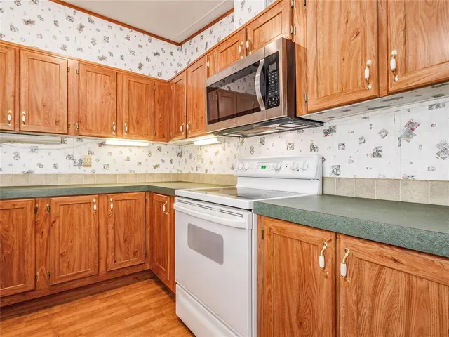 a kitchen with stainless steel appliances granite countertop wooden cabinets a sink and a microwave