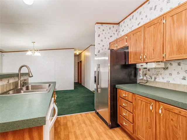 a kitchen with stainless steel appliances wooden cabinets a sink and a refrigerator