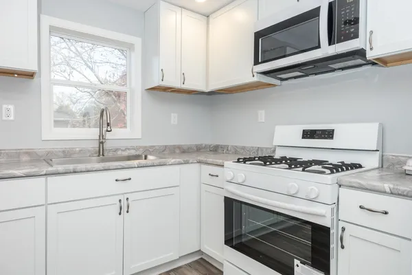 a kitchen with granite countertop white cabinets stainless steel appliances and a window