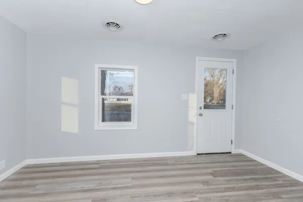 a view of an empty room with wooden floor and a window