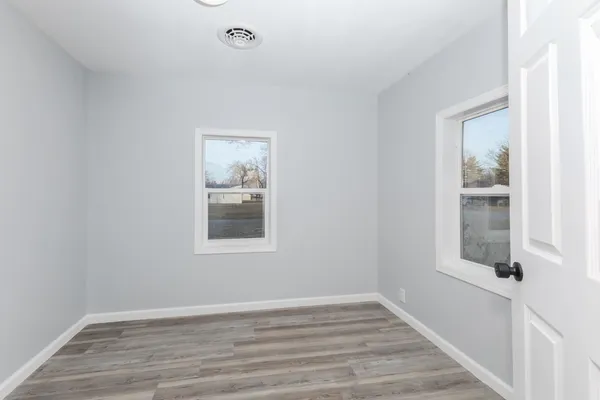 a view of an empty room with wooden floor and a window