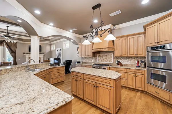 a kitchen with a center island wooden floor and stainless steel appliances