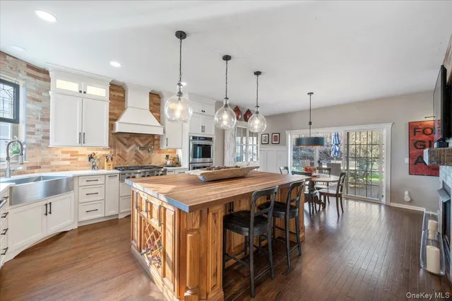a open kitchen with stainless steel appliances granite countertop a stove a refrigerator a kitchen island a dining table and chairs with wooden floor