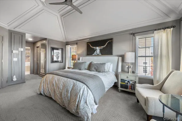 a bedroom with a bed couch and large windows