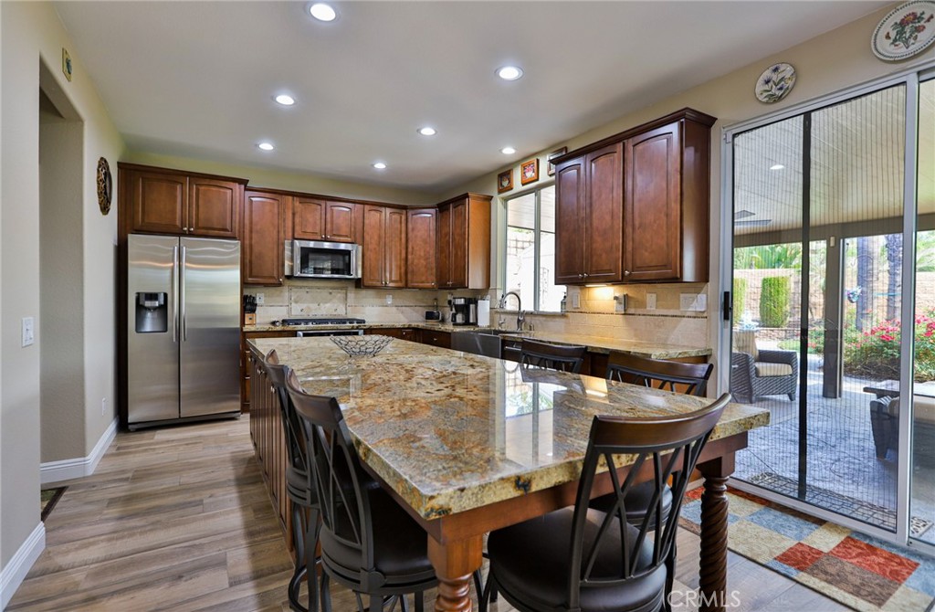 1789 Kapalua Bay Lane Corona, CA 92883 - Photo 19 of 63 a kitchen with granite countertop a table chairs microwave and refrigerator