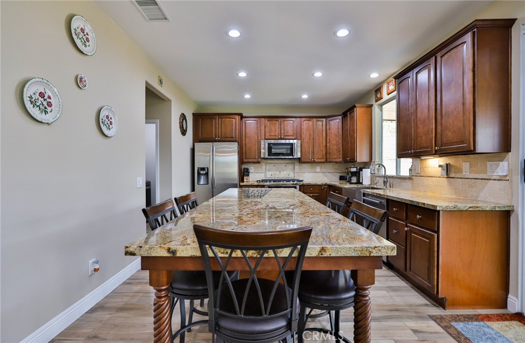 1789 Kapalua Bay Lane Corona, CA 92883 - Photo 20 of 63 a kitchen with stainless steel appliances granite countertop a stove a refrigerator a sink a dining table and chairs