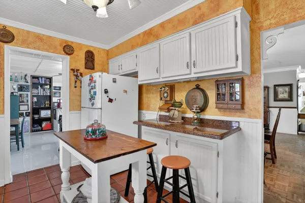 a kitchen with stainless steel appliances granite countertop a table chairs in it and white cabinets