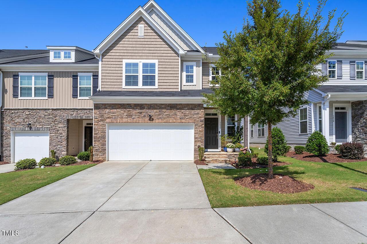 a front view of a house with a garden and trees