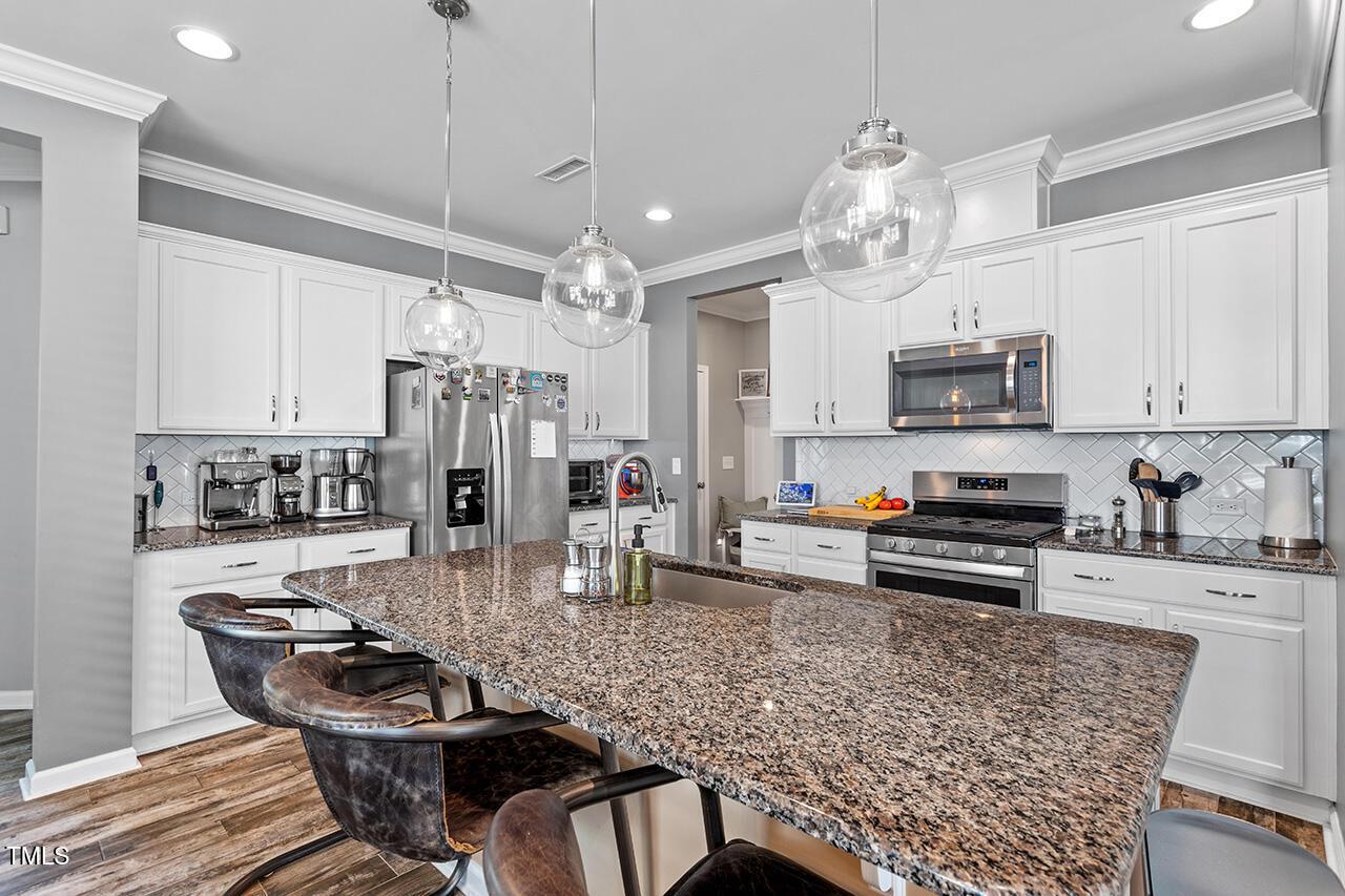 1420 Southpoint Trail Durham, NC 27713 - Photo 6 of 33 a kitchen with stainless steel appliances granite countertop a stove top oven a refrigerator a sink a dining table and chairs with wooden floor