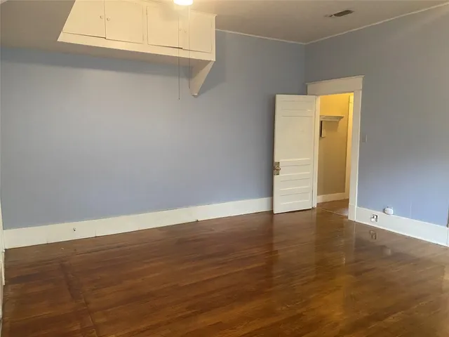 a view of an empty room with wooden floor and closet