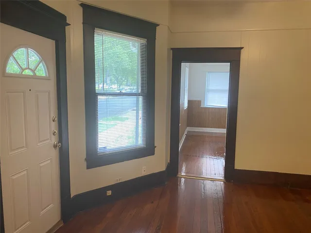 an empty room with wooden floor cabinet and windows