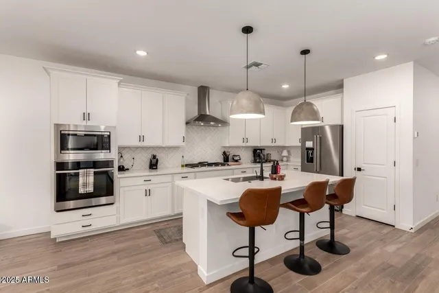 a kitchen with stainless steel appliances kitchen island granite countertop a stove a sink and a refrigerator