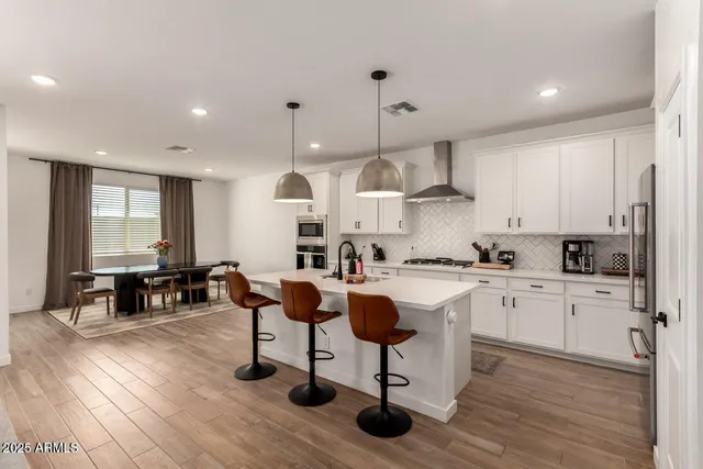 a kitchen with stainless steel appliances granite countertop a stove top oven a sink dishwasher a dining table and chairs with wooden floor