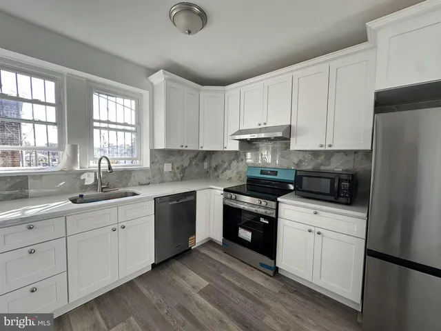 a kitchen with white cabinets appliances a sink and a window