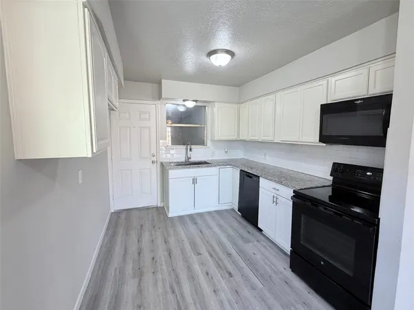 a kitchen with granite countertop white cabinets and black appliances
