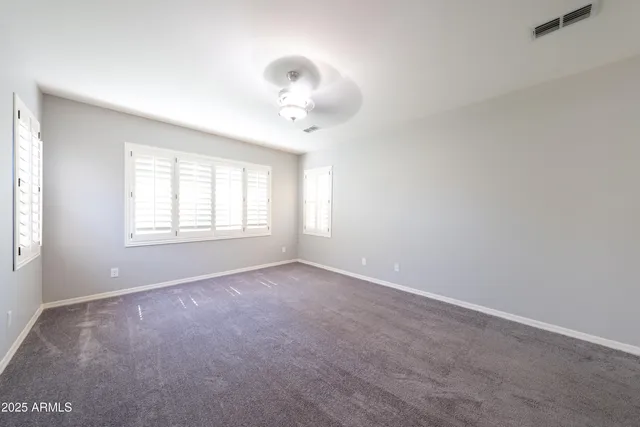 an empty room with windows and chandelier fan