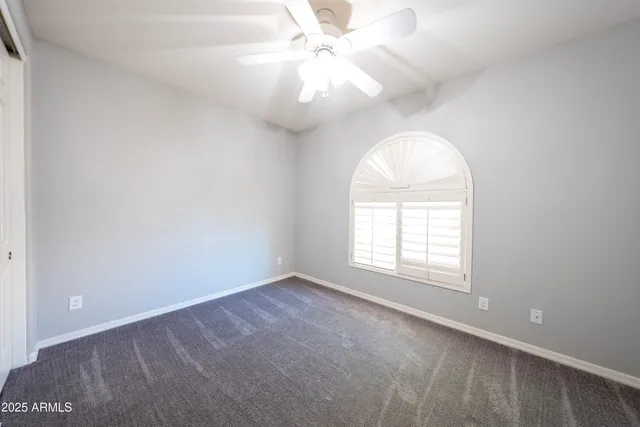an empty room with windows and ceiling fan