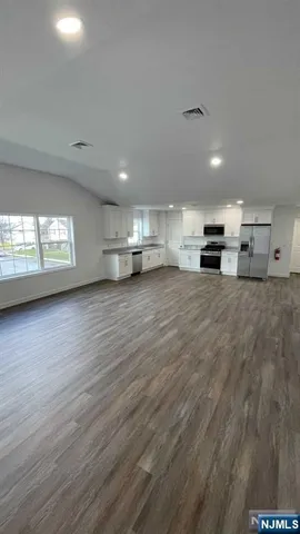 a view of an empty room with window and wooden floor