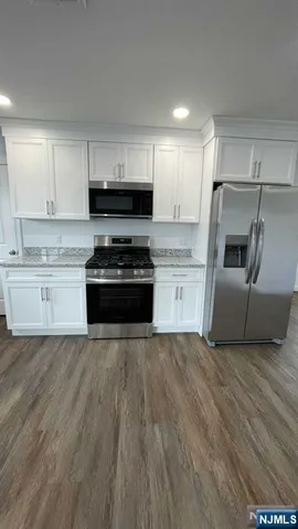 a kitchen with granite countertop a stove a sink and a refrigerator