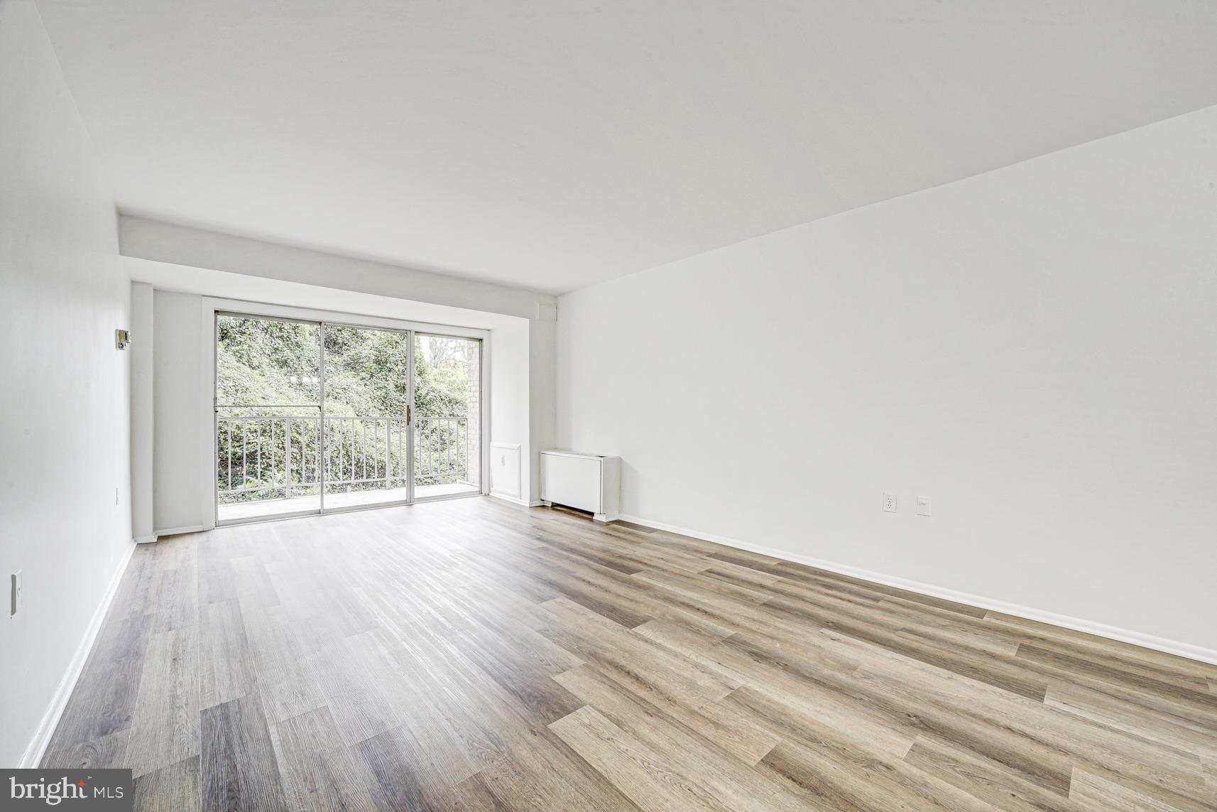 9250 Edwards Way, Unit 207A Hyattsville, MD 20783 - Photo 9 of 17 a view of an empty room with wooden floor and a window