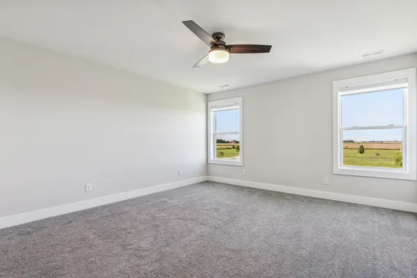a view of an empty room and chandelier fan