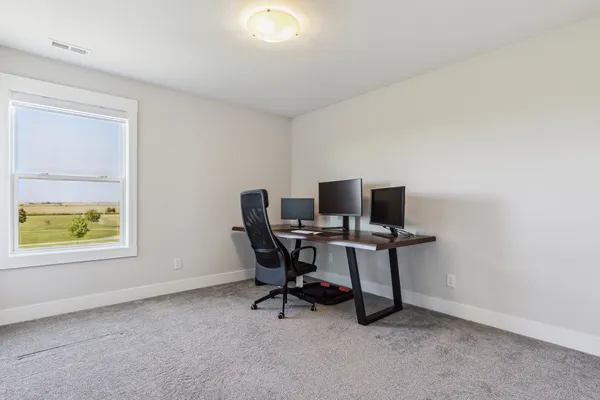 a view of a workspace with furniture and a window